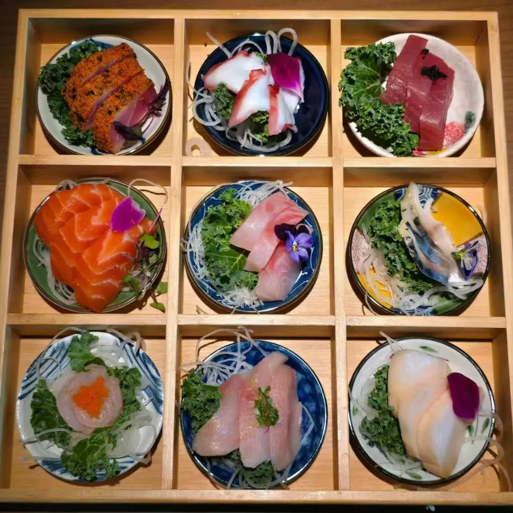 Assorted sashimi platter in a 9-grid wooden box at Machi Sushi, an Asian Restaurant in Houston